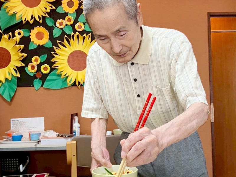 冷やし中華にハムを盛り付ける利用者さま