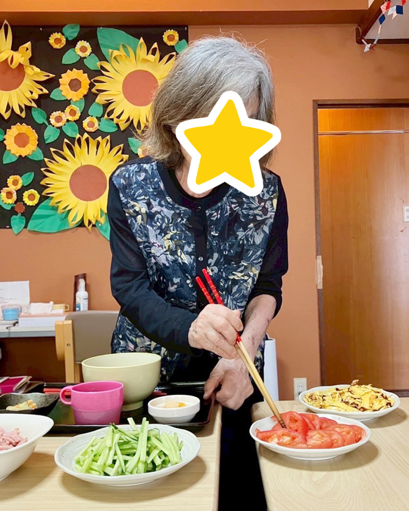 トマトを冷やし中華に盛り付ける利用者さま