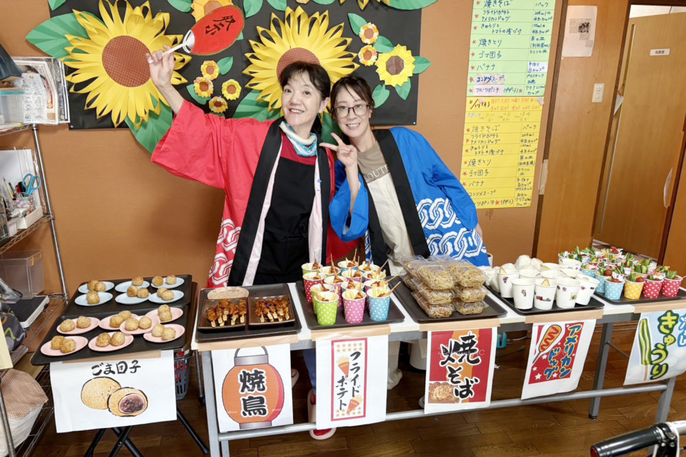 法被を着て屋台越しに記念撮影するスタッフ