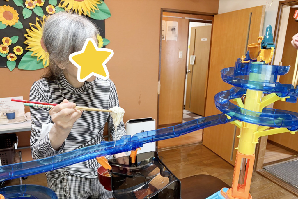 流しそうめん器からそうめんをすくい取った利用者さま