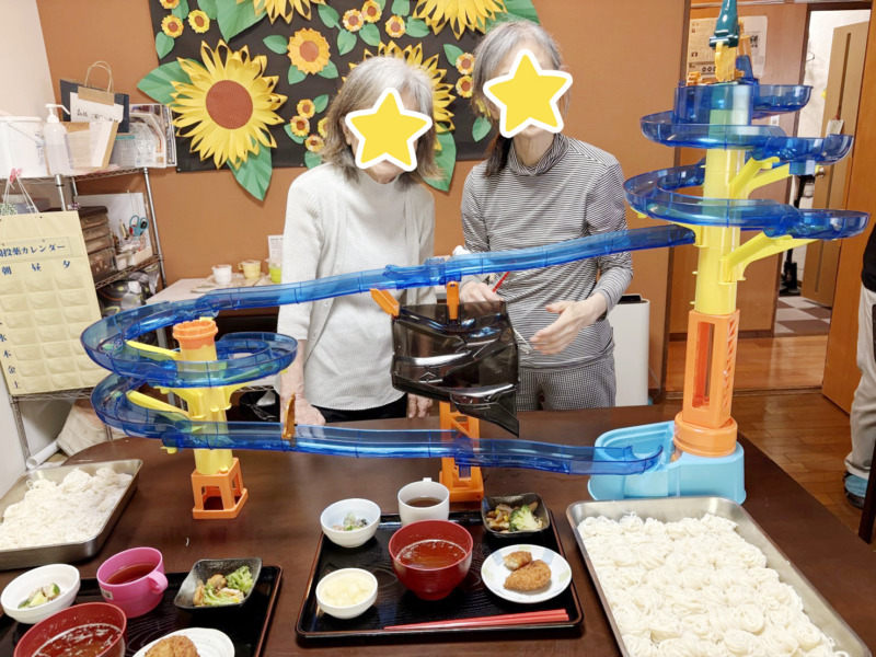 流しそうめん器の後ろで笑顔の利用者さま