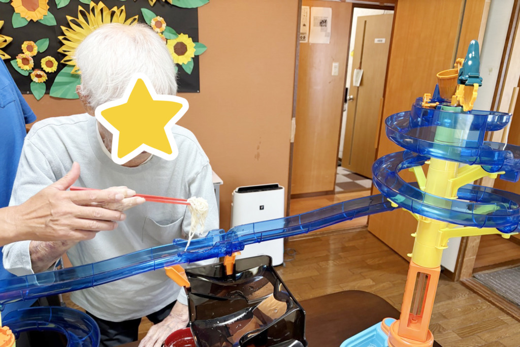 流しそうめん器からそうめんをすくい取った利用者さま