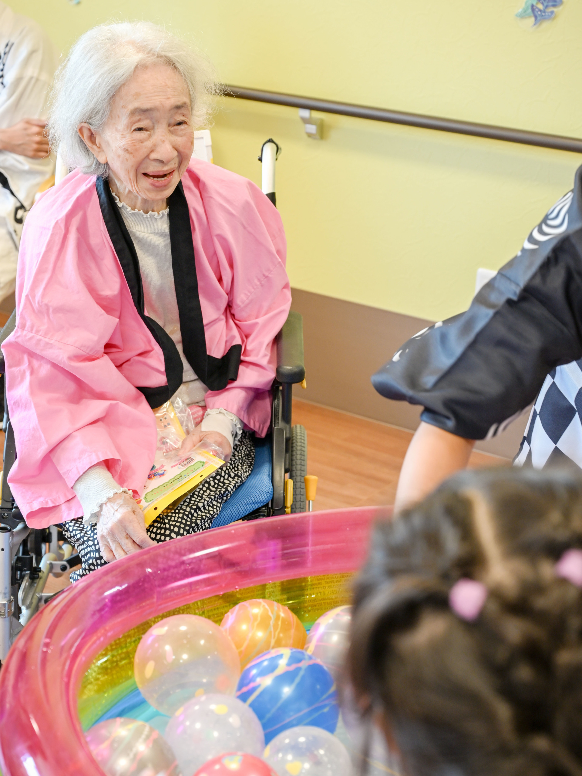 子どもたちと向かい合ってヨーヨー釣りをして笑顔の利用者さま