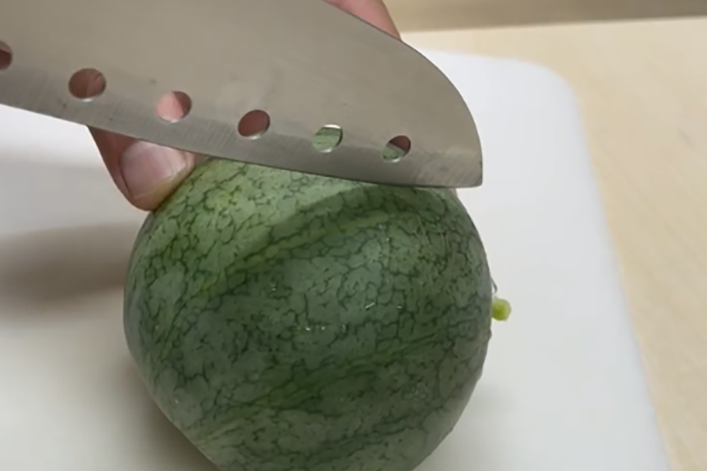 収穫した小玉スイカに包丁を入れるところ