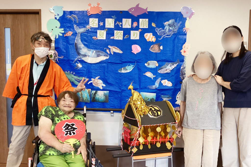 お神輿を挟んで写真に写るスタッフと利用者さまのペア2組