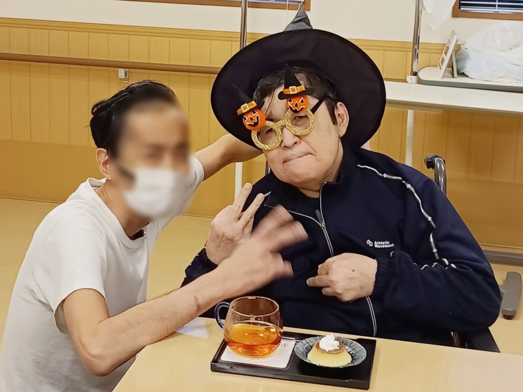 みのりあカフェのアフタヌーンティーを前に仮装してピースする入居者さまとスタッフたち