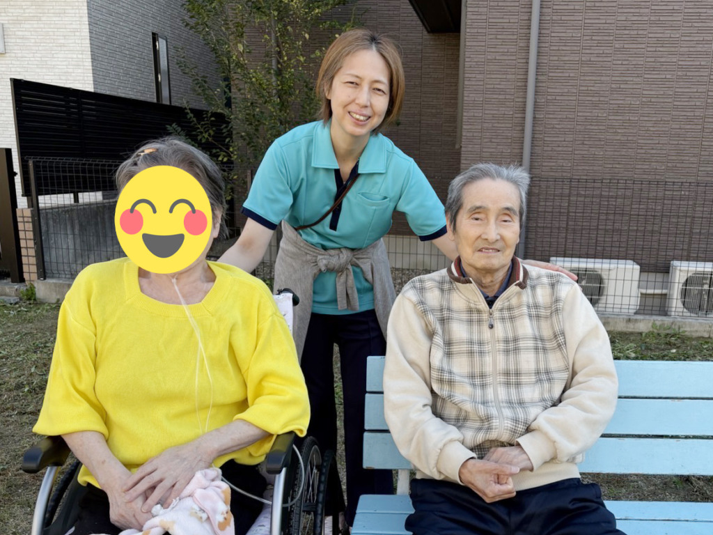 スタッフを挟んでベンチに座って笑顔で写真に写る利用者さまたち