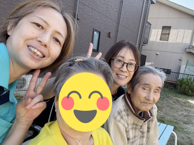 公園のベンチで並んで写真に写る利用者さまとスタッフたち