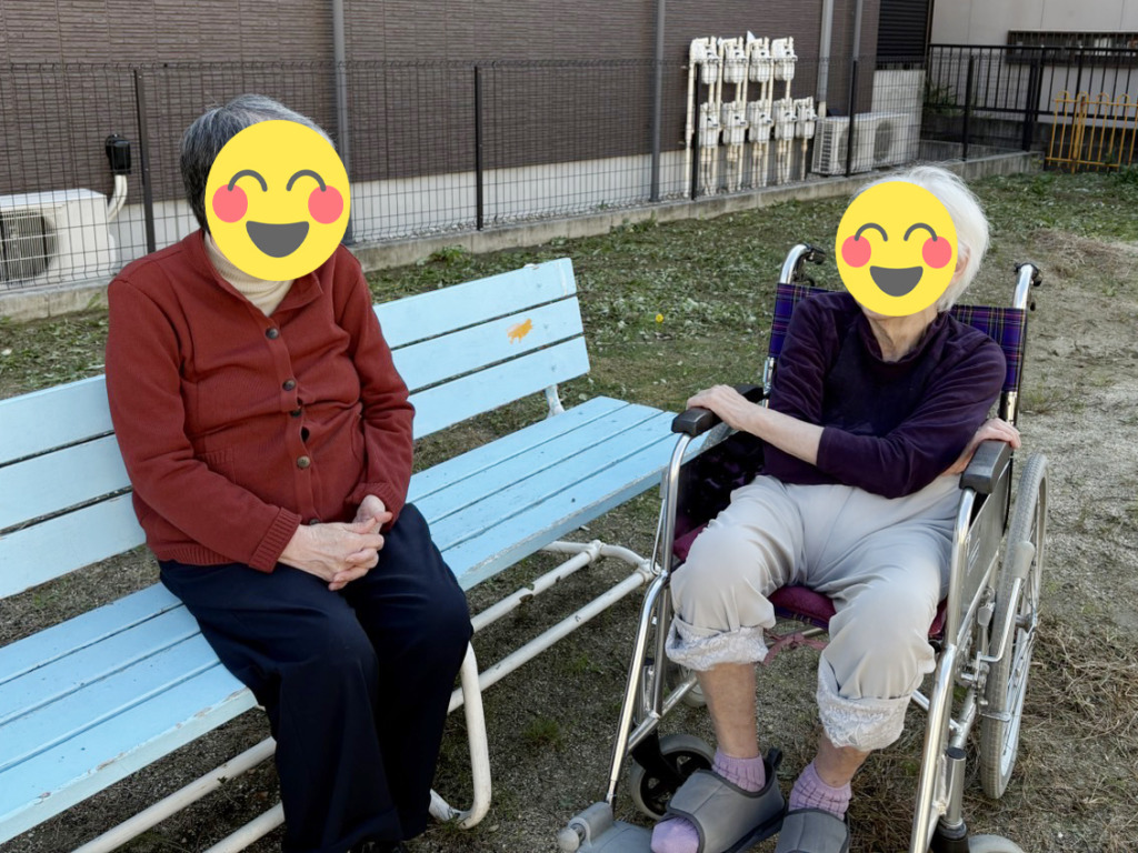 ベンチと車椅子に座って談笑する利用者さまたち