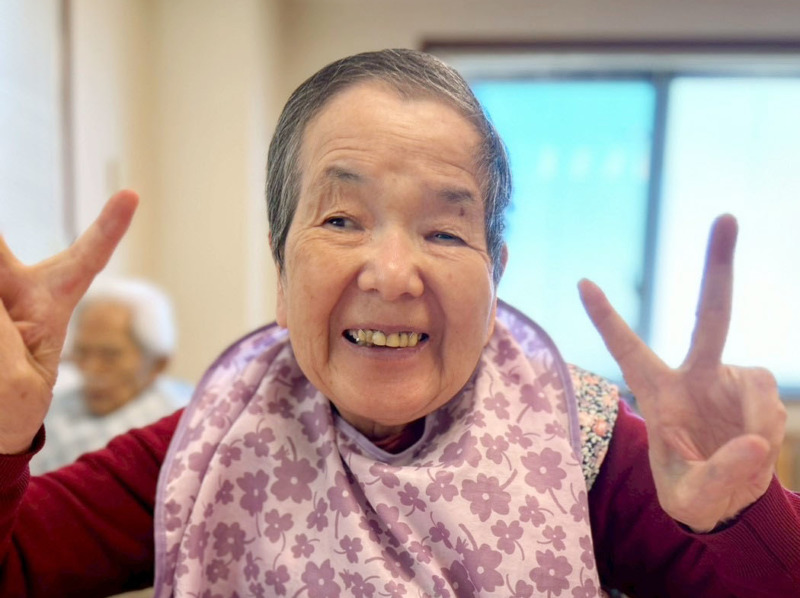 デザートを前に両手でピースを作って笑顔の入居者さま