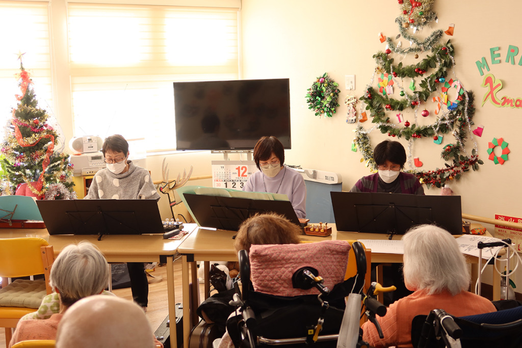 入居者さまの前で演奏を披露するM4の皆さん