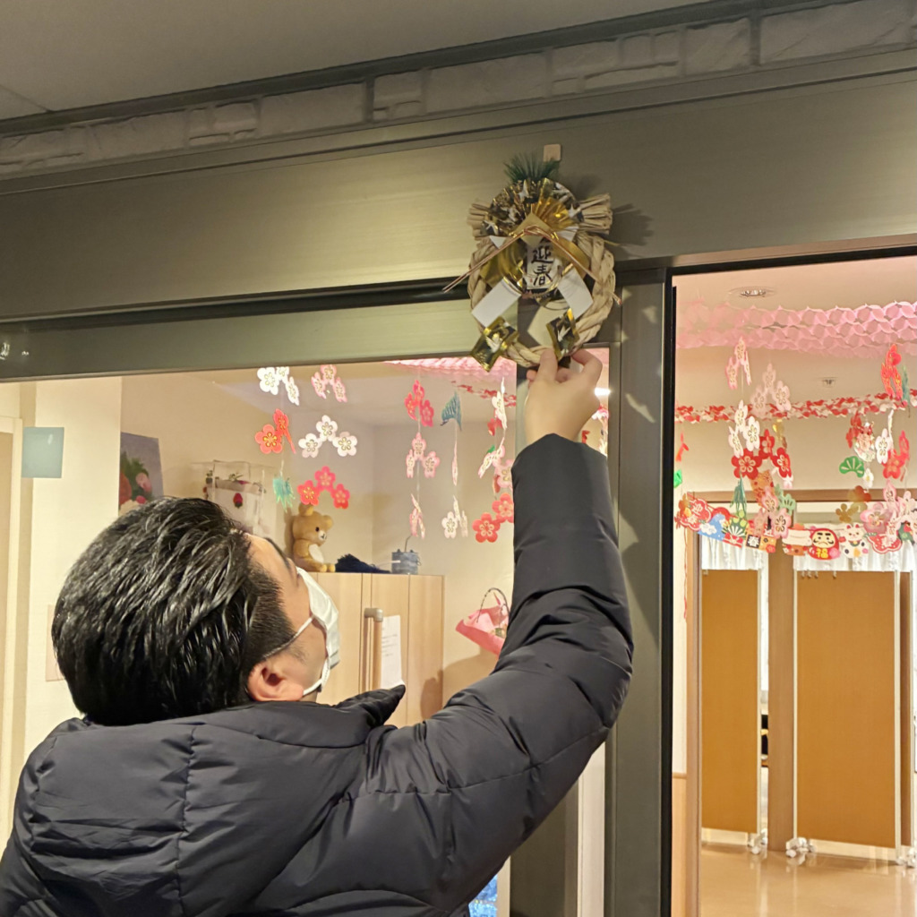 ナーシング和楽縁みどりの入口にしめ縄を飾るマネージャー