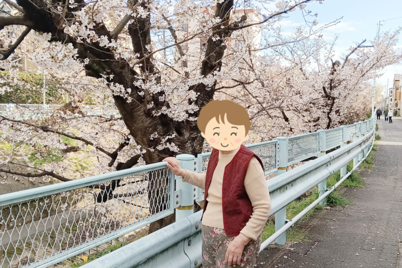 山崎川の桜を背に写真に写る入居者さま